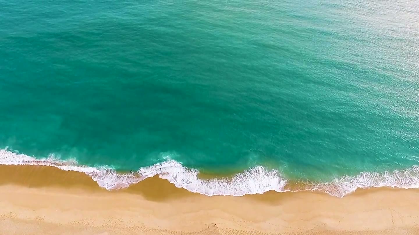 Il mare verde e le onde che raggiungono una spiaggia, senza arredi