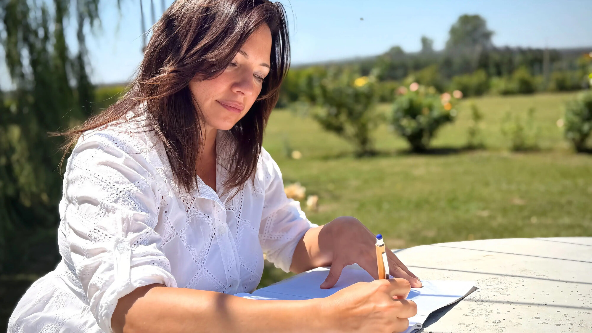 Silvia scrive a penna sul quaderno, nel giardino al mattino