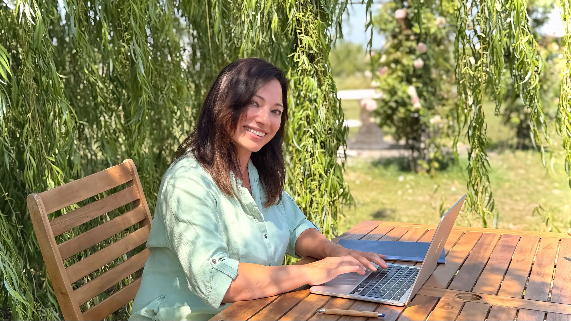 Silvia sorride al laptop, sotto il salice in giardino