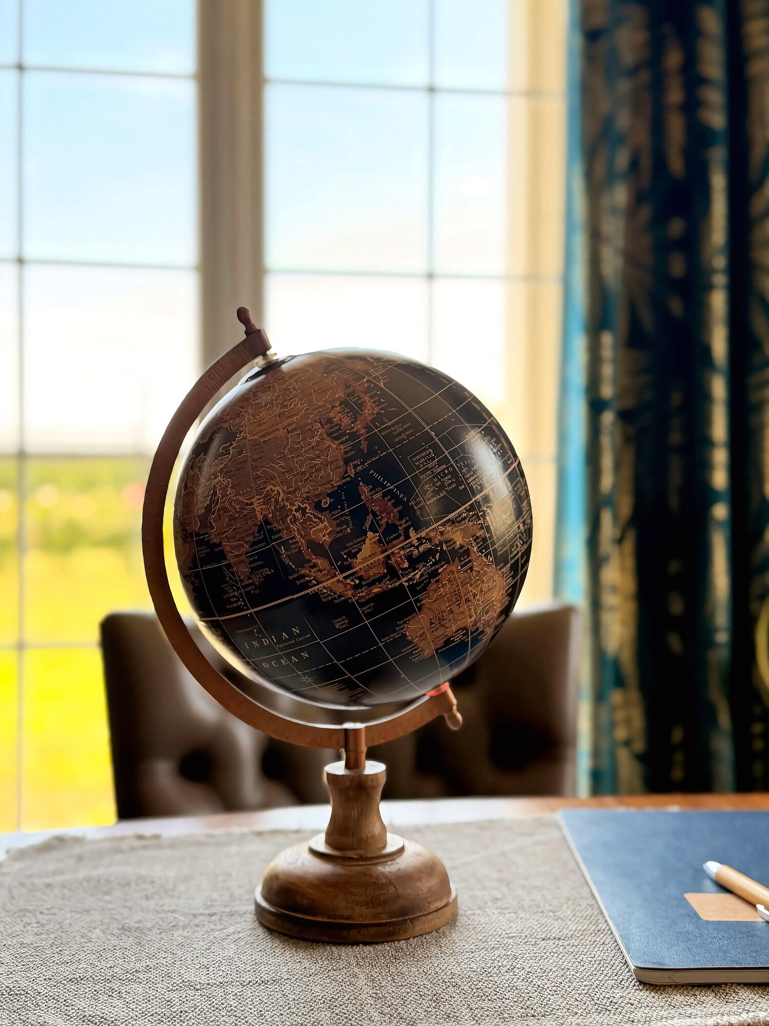 Un mappamondo vintage blu e oro sul tavolo, davanti a una finestra luminosa